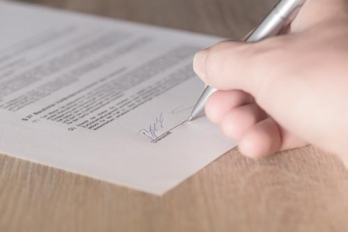 zdjęcie przedstawiające dokument i rękę która go podpisuje